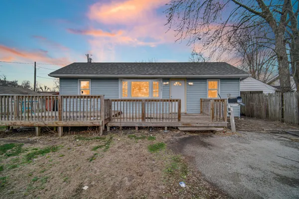 a view of a house with a yard and wooden fence