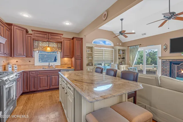 a kitchen with kitchen island granite countertop a stove a sink a dining table and chairs with wooden floor