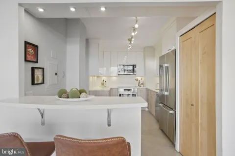 a room with stainless steel appliances a sink dishwasher a refrigerator and cabinets