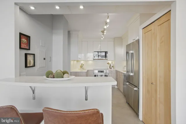 a room with stainless steel appliances a sink dishwasher a refrigerator and cabinets