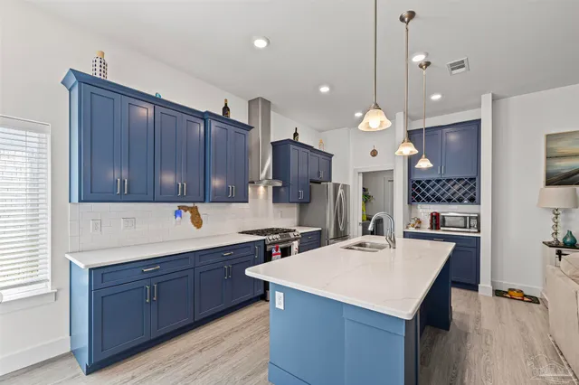 a kitchen with a sink a center island stainless steel appliances and cabinets