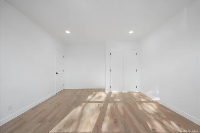 an empty room with wooden floor fireplace and windows
