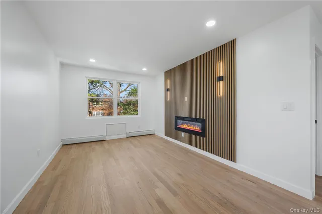 an empty room with windows fireplace and wooden floor