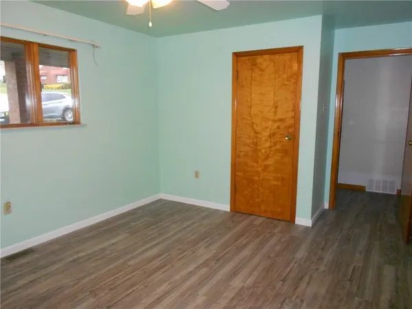 an empty room with wooden floor and windows
