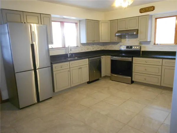 a kitchen with granite countertop a refrigerator sink and cabinets