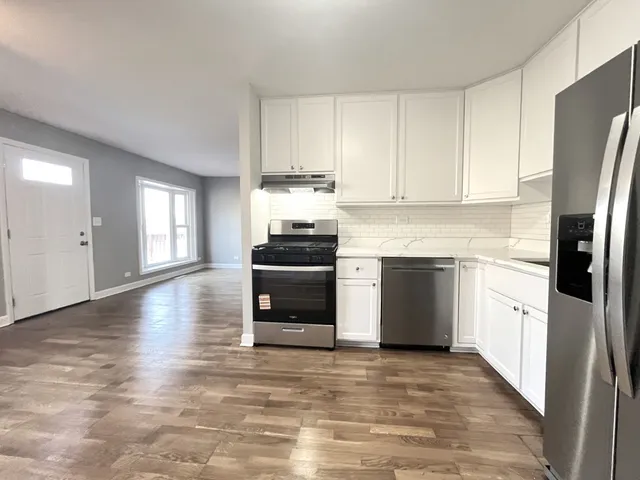 a kitchen with granite countertop a refrigerator stove and white cabinets
