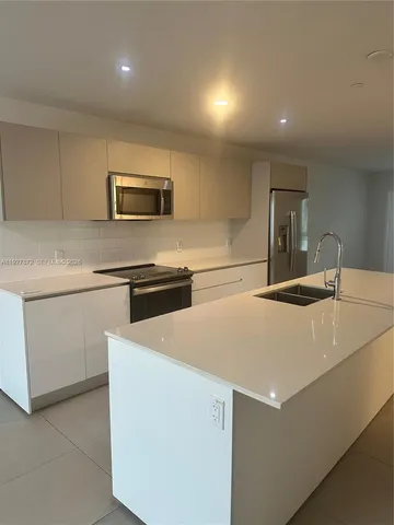 a kitchen with kitchen island a sink a stove and a refrigerator