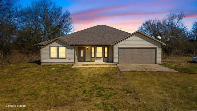 a large tree in front of a house with a yard