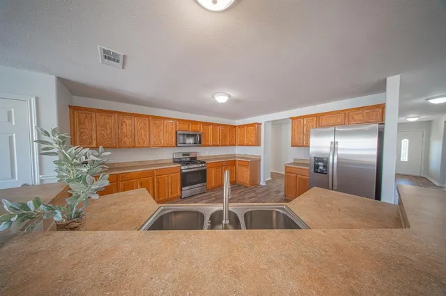 a kitchen with stainless steel appliances kitchen island a large window in front of it