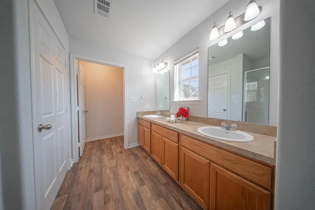 a bathroom with a granite countertop double vanity sink and mirror