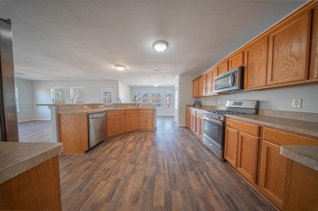 121 Washburn Road North Bells, TX 75414 - Photo 4 of 40 a kitchen with stainless steel appliances granite countertop wooden floors and view of living room