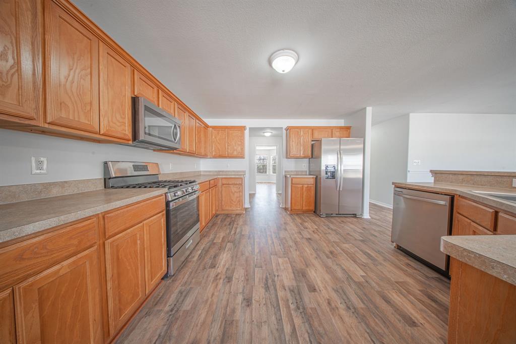 121 Washburn Road North Bells, TX 75414 - Photo 6 of 40 a kitchen with stainless steel appliances granite countertop a refrigerator a stove top oven and wooden floors