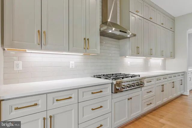 a large kitchen with kitchen island granite countertop a stove a sink a refrigerator and white cabinets with wooden floor