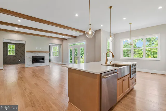 a view of an entryway with wooden floor leading to a furnished livingroom and windows
