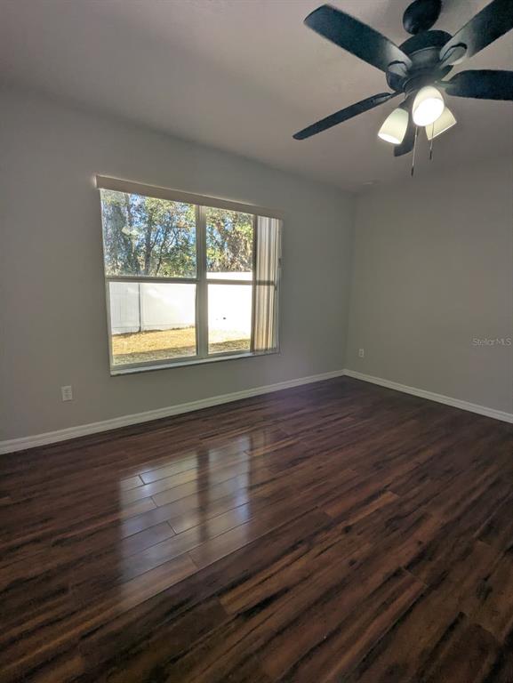 1538 Algonkin Loop Orlando, FL 32828 - Photo 17 of 48 an empty room with wooden floor chandelier fan and windows