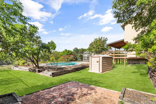 a view of a house with a big yard potted plants and large tree