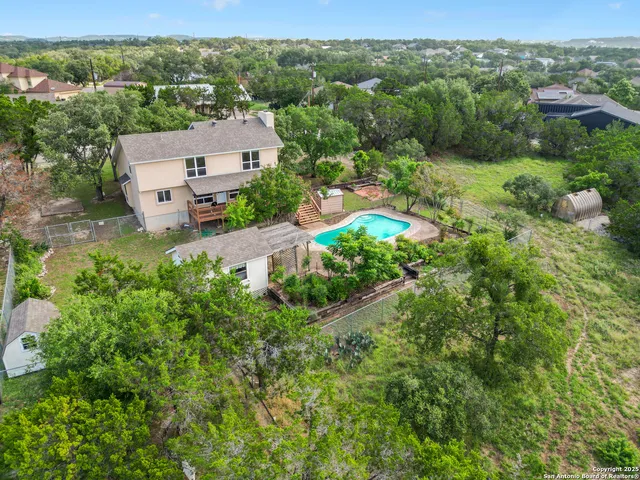 an aerial view of residential houses with outdoor space and trees