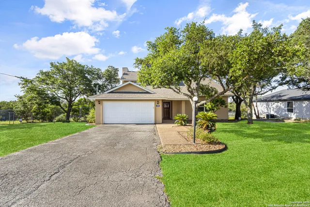 a front view of a house with a garden and trees