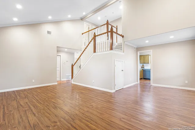 a view of an empty room with wooden floor and a ceiling fan