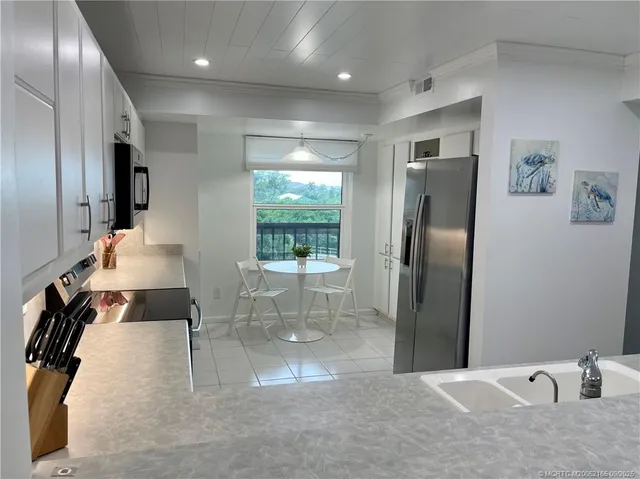 a kitchen with stainless steel appliances kitchen island granite countertop a refrigerator and a sink
