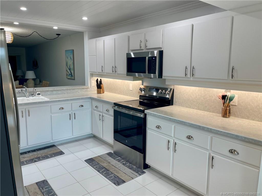 2491 Northeast Ocean Boulevard, Unit 302 Stuart, FL 34996 - Photo 6 of 35 a kitchen with stainless steel appliances granite countertop a sink a stove a microwave and cabinets