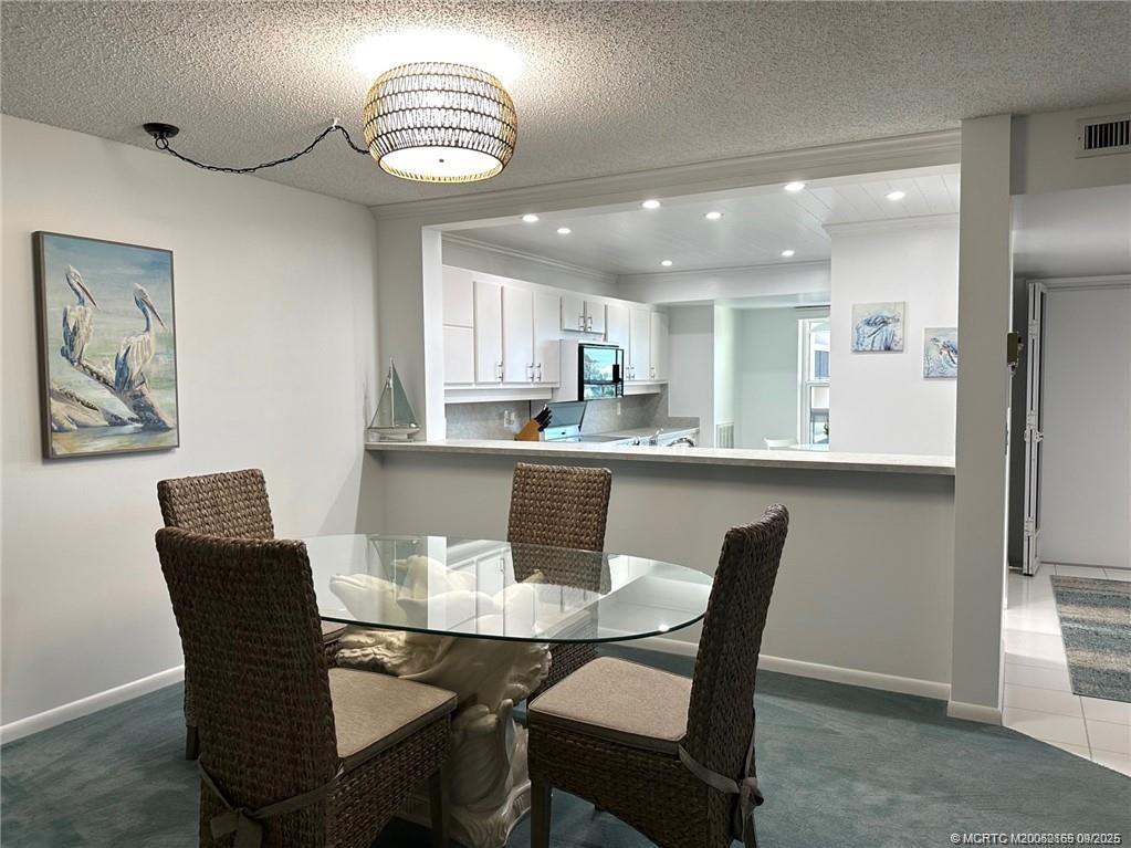 2491 Northeast Ocean Boulevard, Unit 302 Stuart, FL 34996 - Photo 7 of 35 a view of a dining room and a kitchen with a dining table chairs