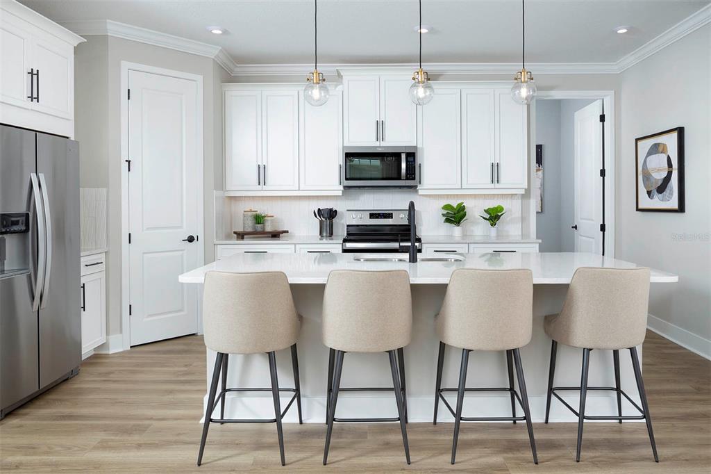 17787 Stillness Court Venice, FL 34293 - Photo 11 of 36 a kitchen with stainless steel appliances granite countertop a dining table chairs refrigerator and microwave