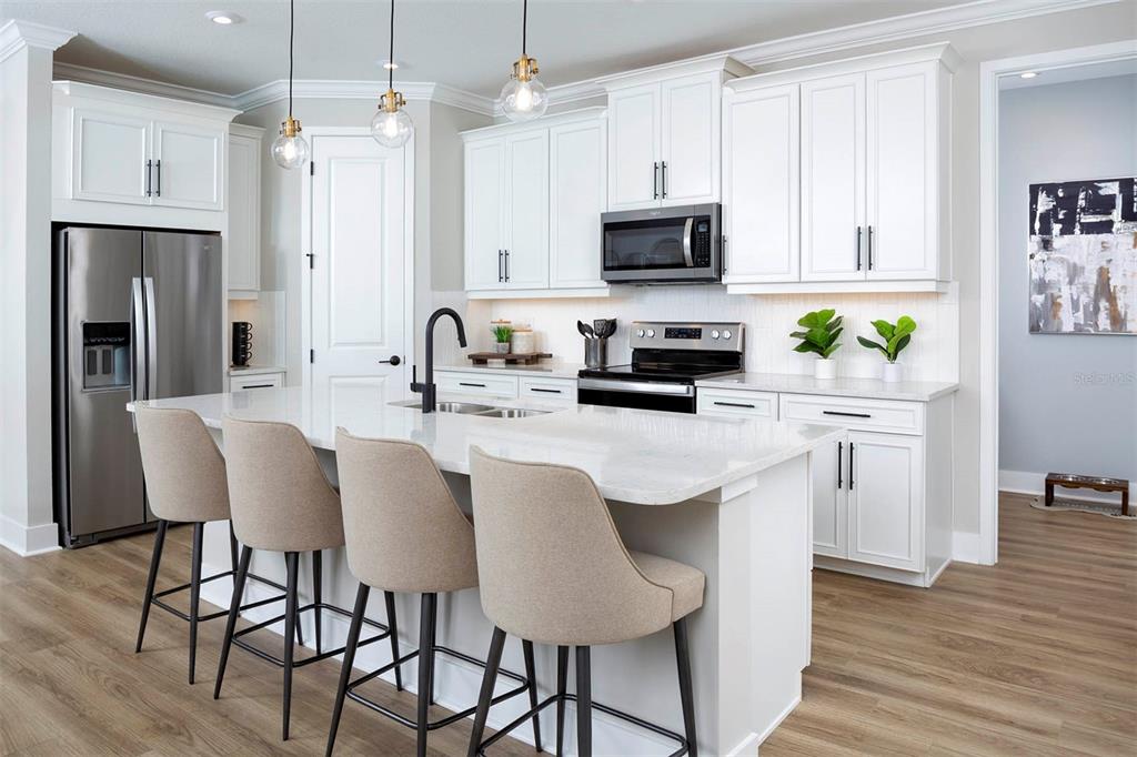 17787 Stillness Court Venice, FL 34293 - Photo 10 of 36 a kitchen with stainless steel appliances granite countertop a table chairs microwave and refrigerator