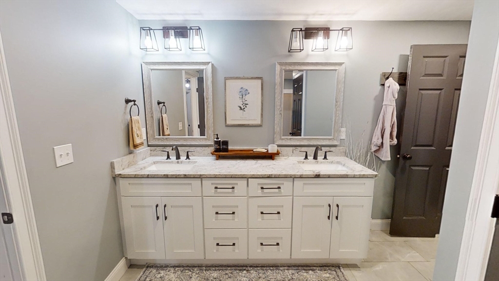223 Old Common Road Lancaster, MA 01523 - Photo 23 of 31 a bathroom with a granite countertop sink a mirror and a shower