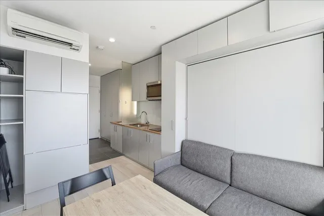 a living room with furniture and a refrigerator