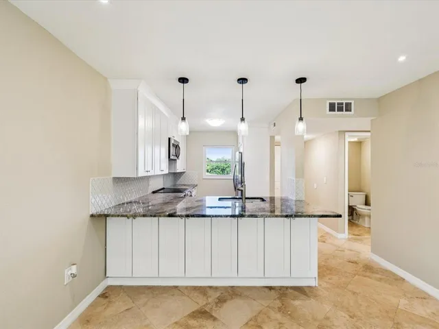 a large white kitchen with kitchen island a sink a stove and a refrigerator with wooden floor