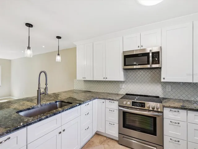 a kitchen with granite countertop a sink window and cabinets