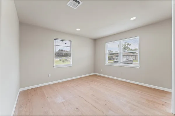 an empty room with windows and ceiling fan