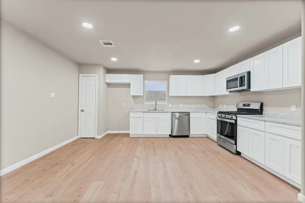 a large kitchen with stainless steel appliances granite countertop a stove a sink dishwasher and a refrigerator with wooden floor