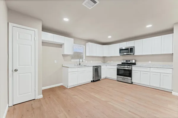 a kitchen with granite countertop white cabinets and stainless steel appliances