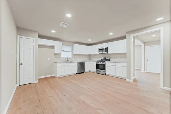 an empty room with wooden floor and natural light