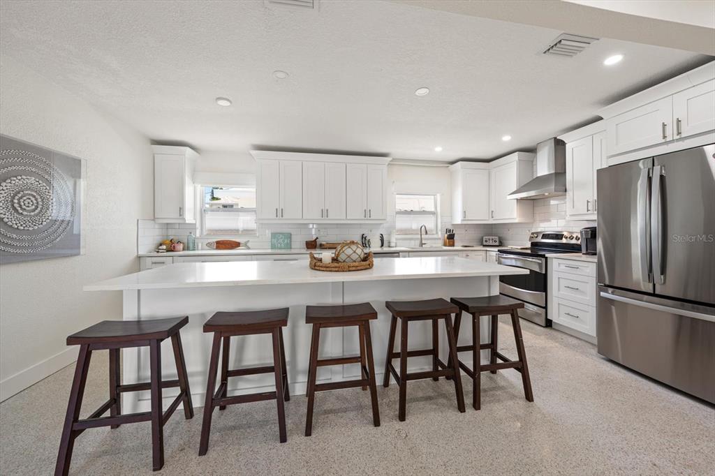 127 11th Avenue Indian Rocks Beach, FL 33785 - Photo 8 of 63 a kitchen with stainless steel appliances granite countertop a table chairs refrigerator and a sink