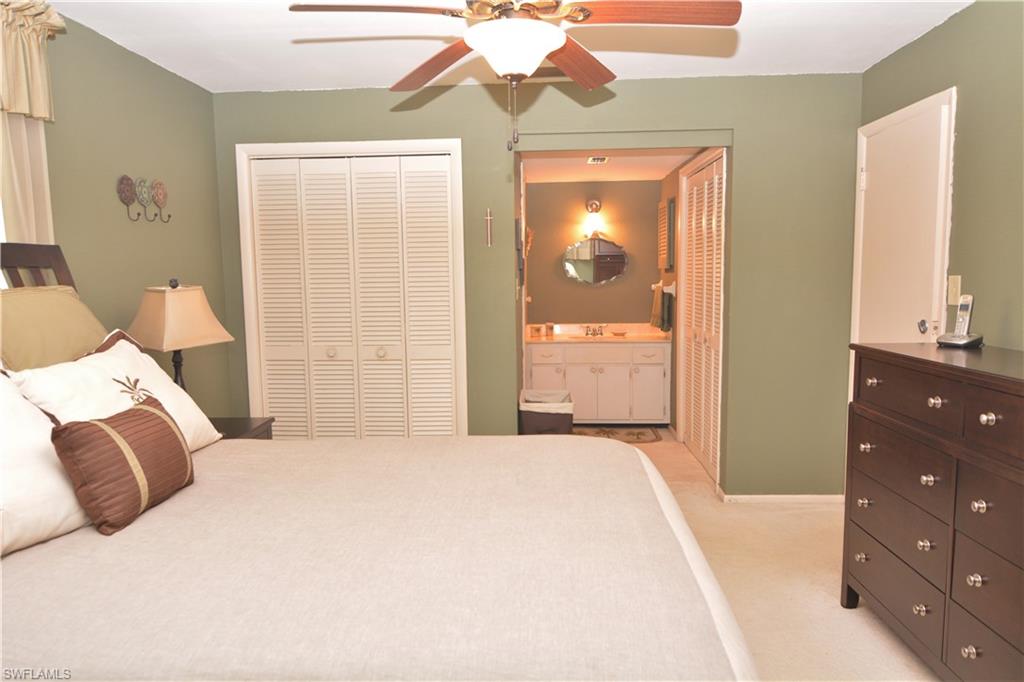 300 Valley Stream Drive, Unit A7 Naples, FL 34113 - Photo 12 of 23 a bedroom with a bed and a chandelier
