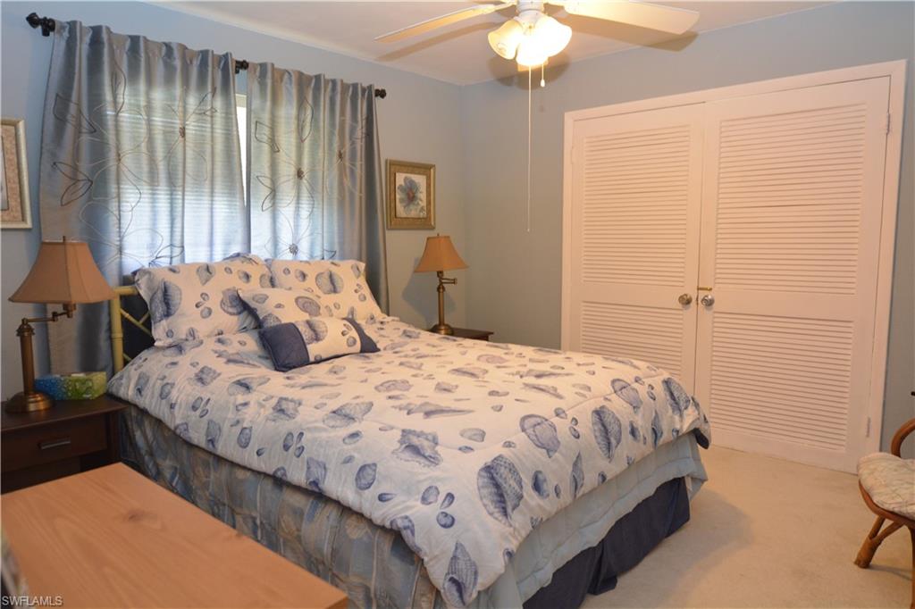 300 Valley Stream Drive, Unit A7 Naples, FL 34113 - Photo 14 of 23 a bedroom with a bed and a chandelier