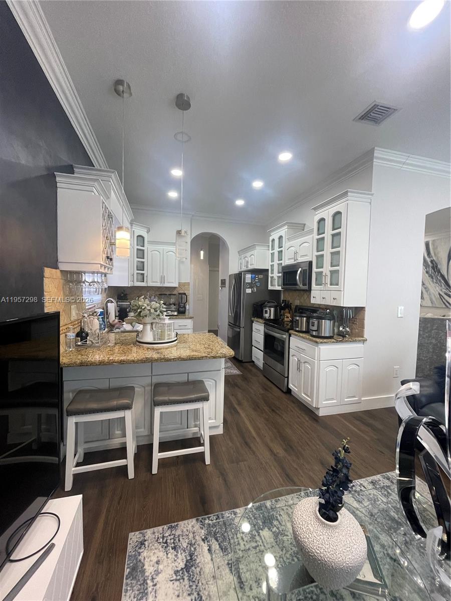 14200 Southwest 160th Court Miami, FL 33196 - Photo 11 of 36 a kitchen with stainless steel appliances kitchen island granite countertop a sink and cabinets