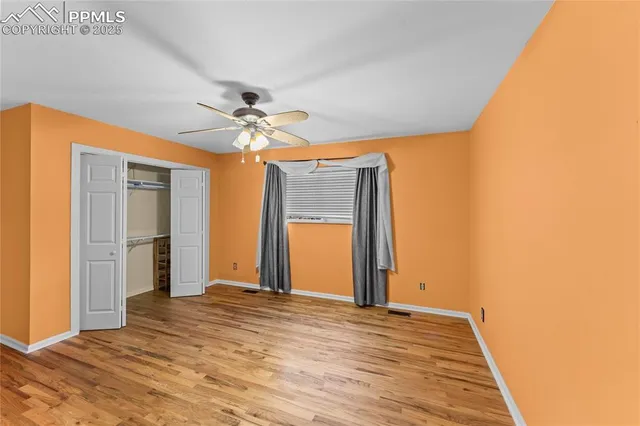a view of a livingroom with a chandelier fan and wooden floor