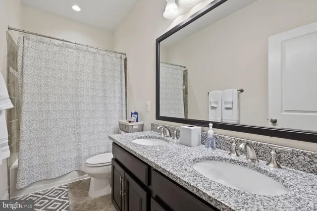 a bathroom with a granite countertop sink a toilet and a mirror