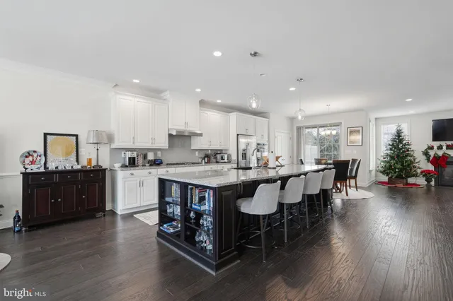 a kitchen with stainless steel appliances granite countertop a table chairs sink refrigerator and cabinets
