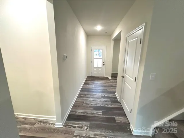 a view of a hallway with wooden floor and a bathroom