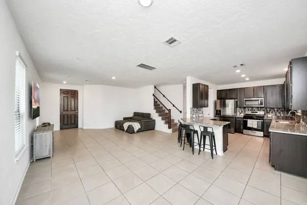 a kitchen with stainless steel appliances kitchen island granite countertop a table chairs and a refrigerator