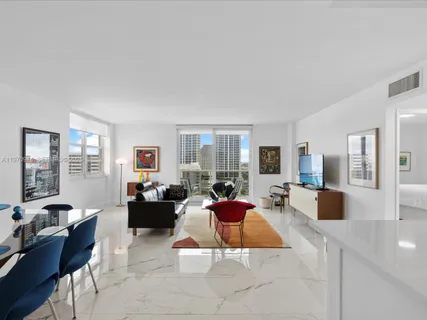 a kitchen with stainless steel appliances granite countertop a refrigerator a stove a sink and a white cabinets with wooden floor