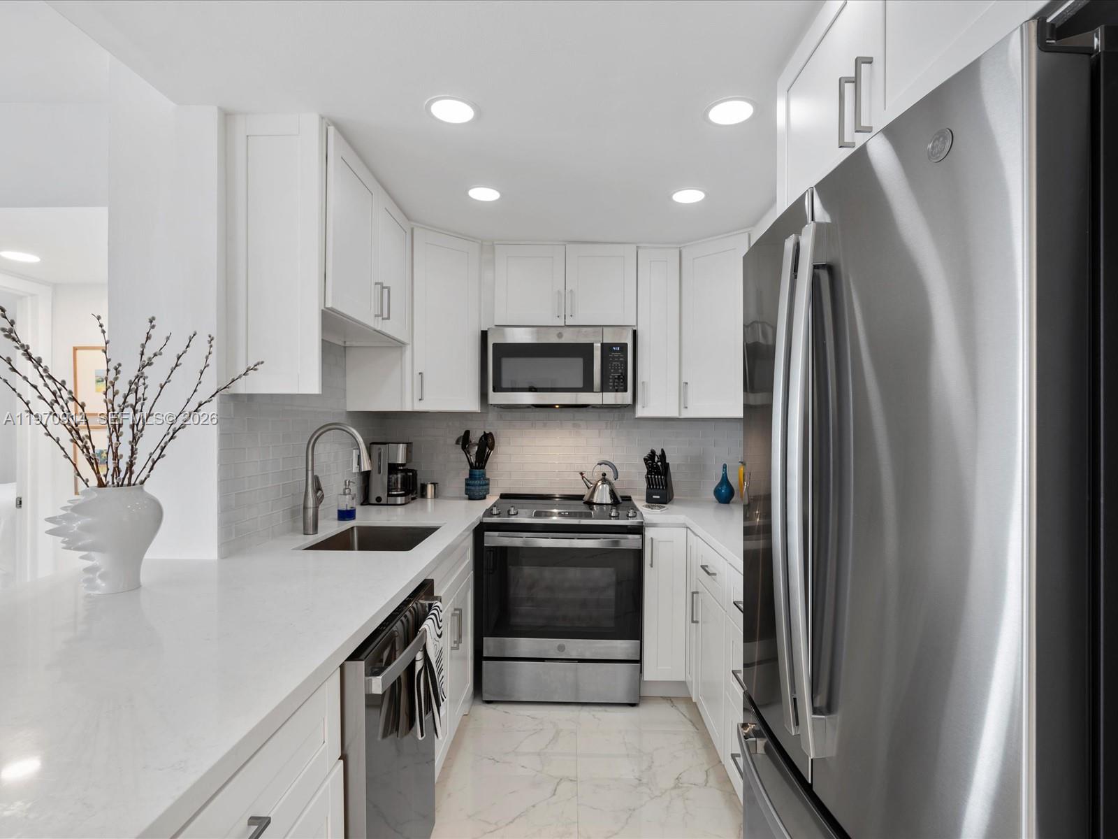 336 North Birch Road, Unit PH Fort Lauderdale, FL 33304 - Photo 5 of 68 a kitchen with stainless steel appliances granite countertop a refrigerator a stove a sink and a white cabinets with wooden floor