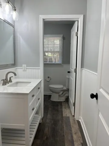 a bathroom with a granite countertop sink a toilet and a mirror