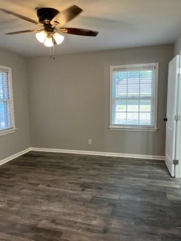 a view of an empty room with window and chandelier fan