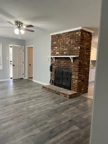 a view of an empty room with wooden floor and a fireplace